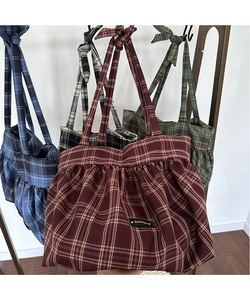 Détail de divers sacs cabas à carreaux en rouge, bleu, vert et noir avec étiquette