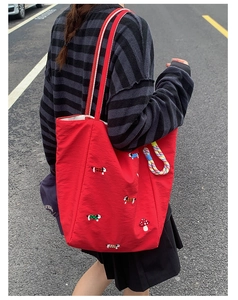 Detail of red canvas tote bag featuring dog embroidery and mushroom pattern outdoors