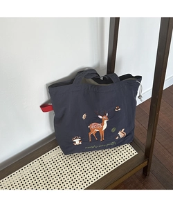 Detail of forest animal embroidery and red ribbon handle on large canvas tote bag