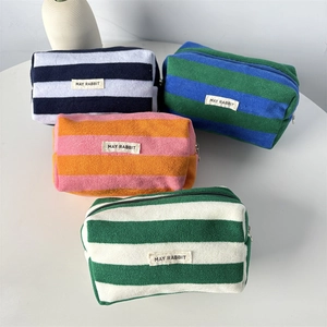 Macro detail of striped terry cloth pencil cases with silver metal zippers and woven labels