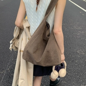 Large dark brown suede tote bag for women worn with a trench coat on a road background