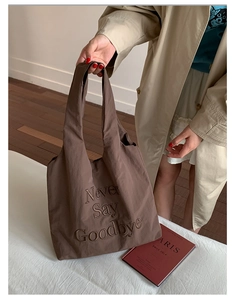 Detailed view of brown nylon tote bag featuring Never Say Goodbye letter embroidery