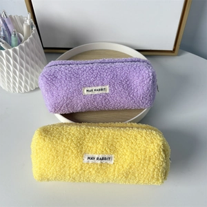 Close-up of soft plush pencil cases in purple and yellow with durable zipper and label