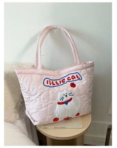 Close-up of pink quilted tote bag featuring heart patterns and a white cat patch detail