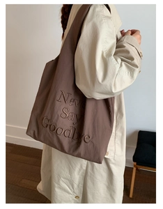 Detail of coffee brown nylon tote bag featuring 'Never Say Goodbye' letter embroidery