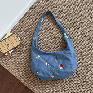 Sac bandoulière en denim bleu avec broderies de forêt et texte bonjour sur tapis tissé