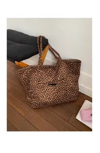 Close-up of leopard print tote bag with black leather label on soft canvas fabric