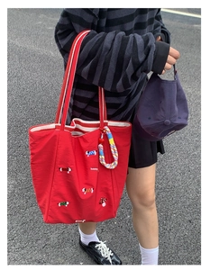 Detailed view of red canvas tote with colorful dog embroidery and striped shoulder strap
