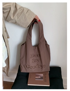 Detail of brown nylon tote bag with Never Say Goodbye letter embroidery and shoulder strap