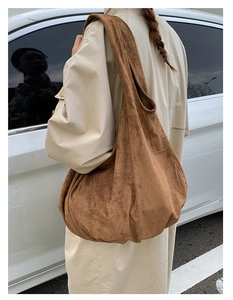 Detailed texture of brown suede tote bag carried by a woman wearing a beige trench coat