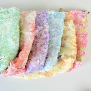 Close-up of colorful floral plush makeup bags with soft texture and metal clasp closure
