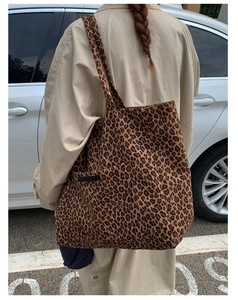 Detailed side view of the leopard print tote bag with black rectangular brand label