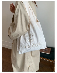 Detail of white nylon tote bag with high-quality Never Say Goodbye embroidery on it