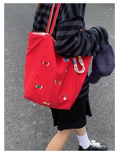 Close-up of red canvas tote bag featuring cute dog embroidery and mushroom patterns
