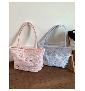 Detail of quilted tote bags featuring heart patterns and cute cartoon embroidery