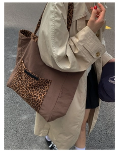 Detailed view of canvas tote bag featuring leopard print pocket and sturdy brown straps