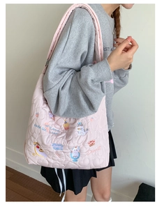 Detail showing heart-quilted texture and cute cat embroidery on pink tote bag