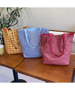Close-up of three colorful checkered canvas tote bags in yellow blue and red on wooden table