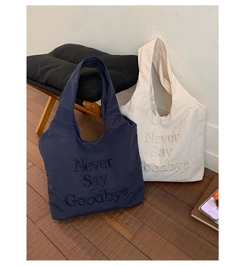 Detail of navy and beige nylon tote bags with Never Say Goodbye letter embroidery