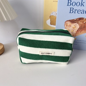 Close-up of green and white striped terry cloth pencil case with May Rabbit woven label