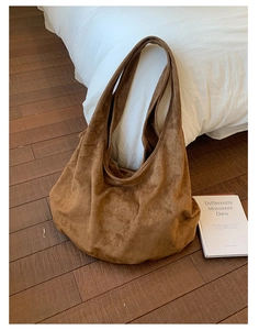 Detailed close-up of brown suede tote bag with matte texture in a cozy indoor setting