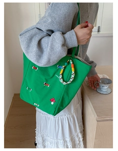 Detail of vibrant green canvas tote with cute dog embroidery and a colorful rope charm