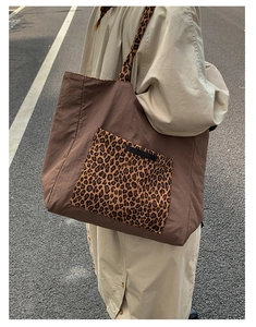 Detail view of the leopard print pocket and shoulder strap on a large canvas tote bag