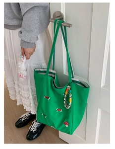 Detail of green canvas tote with dog and mushroom embroidery hanging on a door