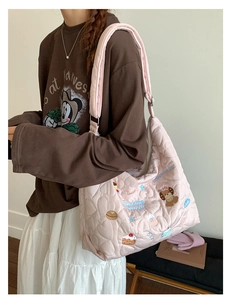 Detail of pink heart-quilted tote bag featuring cute cartoon bear and cake embroidery