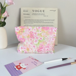 Detailed close-up of pink floral plush makeup bag with branded label and zipper closure