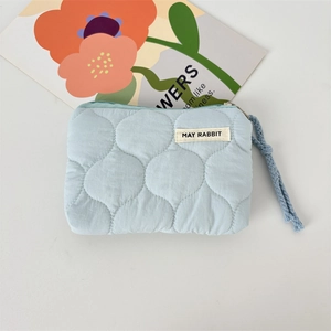 Gros plan détaillé d'une pochette matelassée bleu clair avec étiquette tissée et cordon tressé