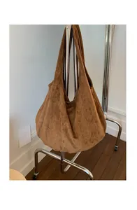 Detailed view of the large brown suede tote bag hanging on a modern metal display stand