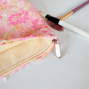 Detail of pink floral tweed makeup bag showing silver zipper and thick canvas lining