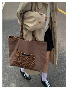 Close-up of leopard print shoulder strap and pocket on large brown canvas tote bag
