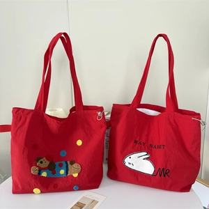 Detail of red nylon tote bags with cute cartoon bear and rabbit embroidery patterns