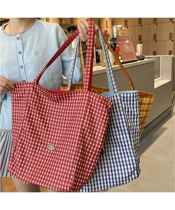 Close-up of large plaid canvas tote bags set featuring metal logo plates in three colors