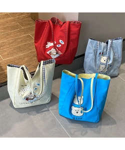 Close-up of colorful canvas tote bags with bear embroidery and checkered lining details