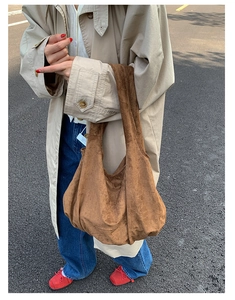 Close-up of brown suede hobo bag worn with beige trench coat for autumn style