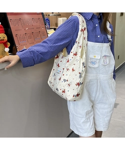 Detail of cream quilted tote bag with cute cartoon dog patterns and fabric label