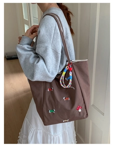 Detail of coffee brown canvas tote bag featuring mushroom and dog embroidery