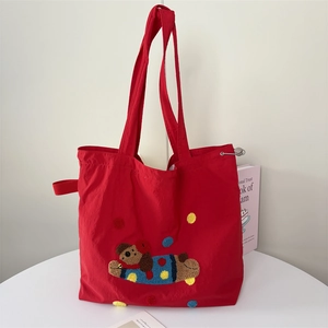 Red large capacity nylon tote bag with cartoon dog embroidery on white table