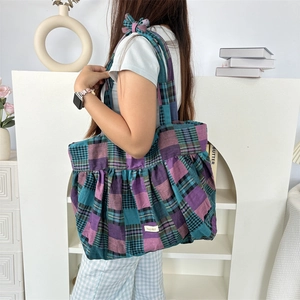 Détail d'un grand sac cabas à carreaux violets avec bordure plissée et nœud sur la bandoulière