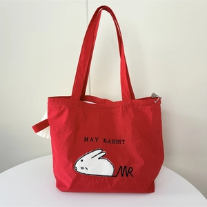 Detail of red nylon tote bag with white rabbit embroidery and sturdy double handles