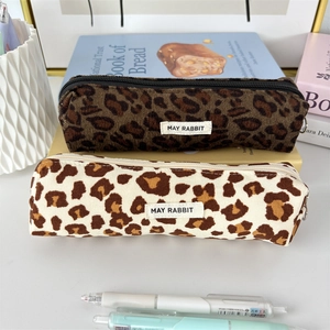 Detailed close-up of leopard print corduroy pencil cases stacked on books