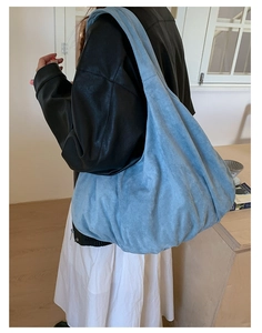 Model wearing large light blue suede tote bag with a minimalist hobo slouchy design