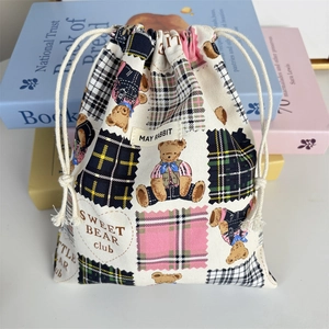 Detail of canvas drawstring bag with bear and plaid pattern near decorative books