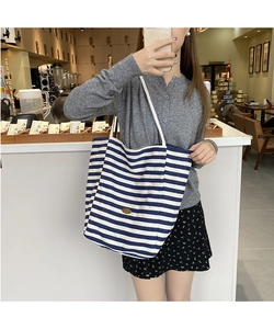 Détail du sac fourre-tout en toile à rayures bleues et blanches avec patch logo