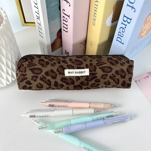Close-up of leopard print corduroy pencil case with pastel pens on a desk