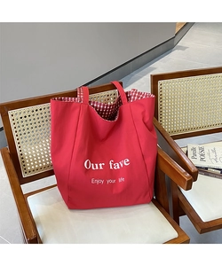 Detail view of red canvas tote bag showing artistic text and red checkered lining detail