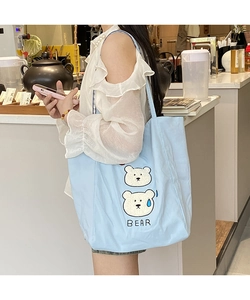 Detail shot of light blue canvas tote bag featuring cute cartoon bears and text